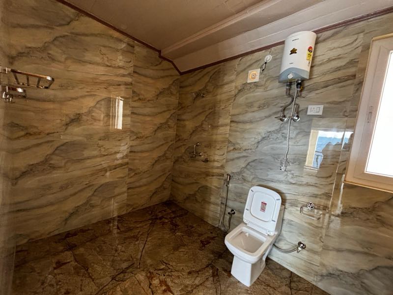 Attached bathroom with marble walls, an open shower area and a window to the hillside