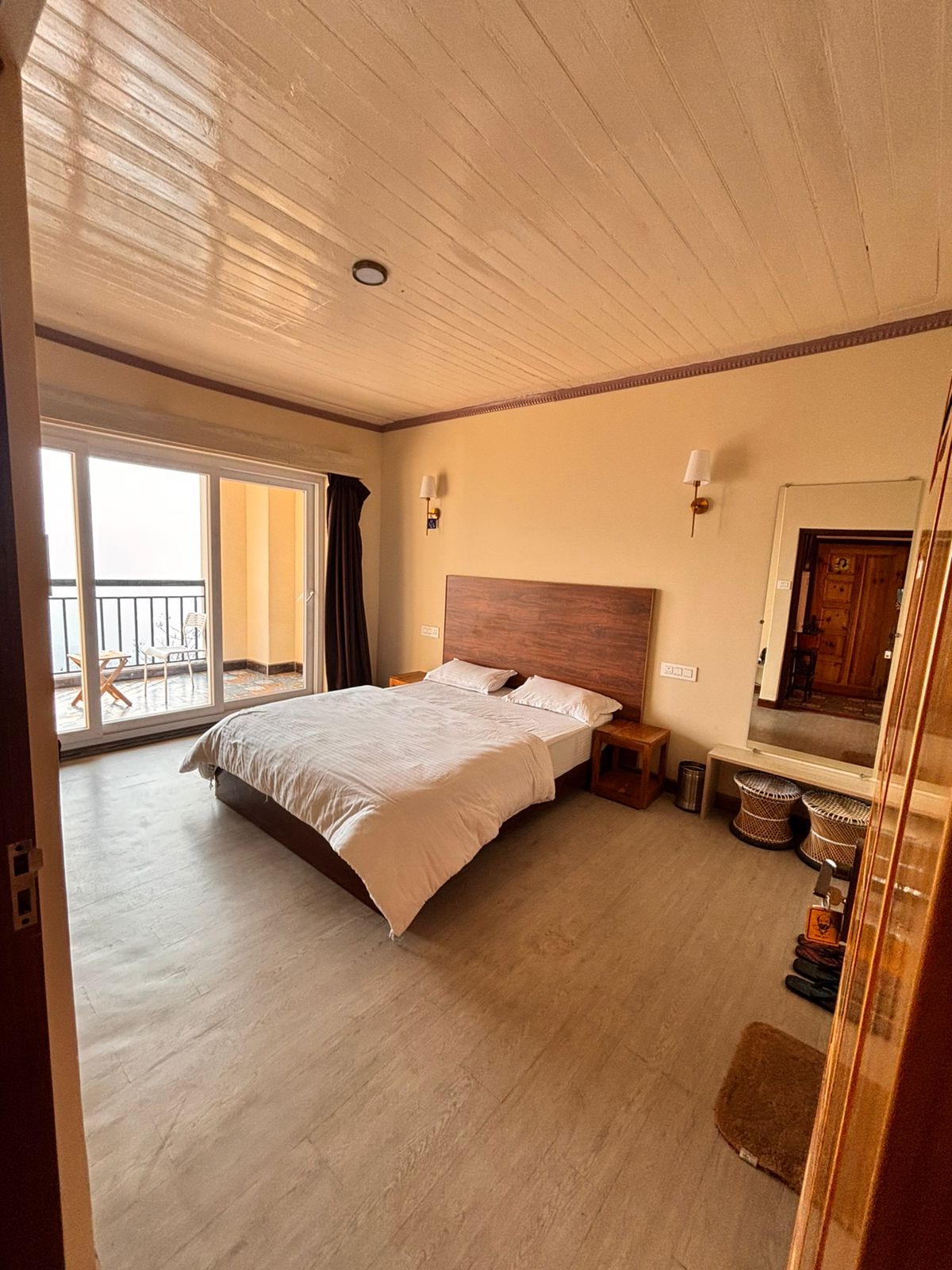 The Erick Avari room: a wide bed facing sliding balcony doors, with a full-length mirror opposite